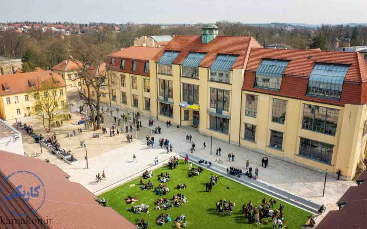 فضای بیرونی دانشگاه هنر و تکنولوژی باوهاوس (Bauhaus) آلمان با دانشجویانی که در محوطه قدم می‌زنند یا روی چمن‌ها و نیمکت‌ها نشسته‌اند. 