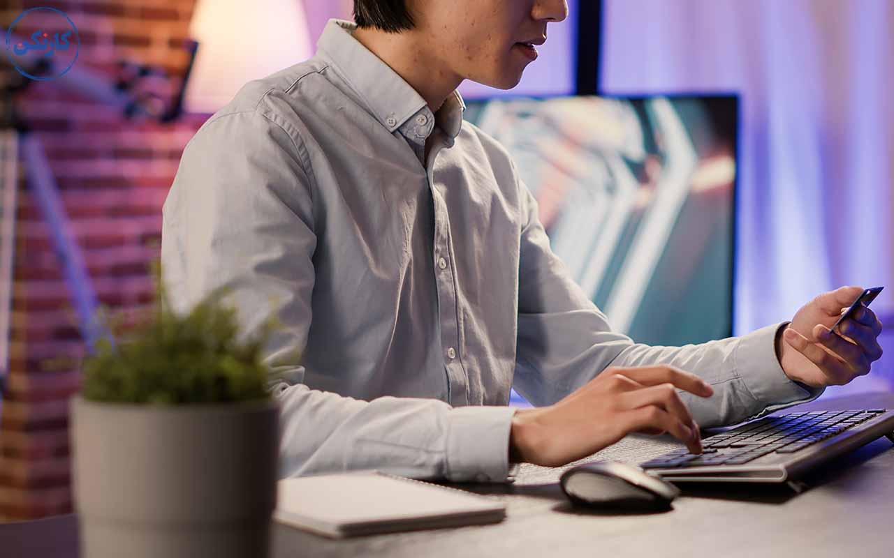 یک مرد پشت میز نشسته و مشغول انجام دادن کارهایش به صورت اینترنتی است.