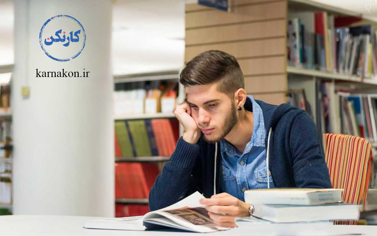 دانشجوی پسر در حال مطالعه در کتابخانه یکی از دانشگاه های غیر انتفاعی